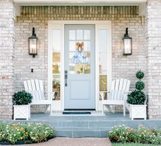 two white chairs sitting in front of a blue and white door on a brick building