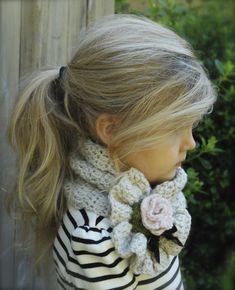 a close up of a doll wearing a knitted scarf with flowers on it's neck