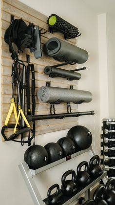 there are many different types of gym equipment hanging on the wall in this room, including dumbbells and kettles