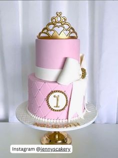 a pink and white cake with a gold crown on top