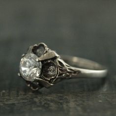 This stunning antique style ring is so romantic! It features sculptural flowers that surround and nestle the center 6mm stone. The stone is held in place by four prongs. You can choose a Cubic Zirconia or a White Topaz. Your ring will be made to size just for you and oxidized and polished for an antiqued look.Deb is a professional jeweler that has dedicated over 15 years to her craft. Please don't hesitate to contact us with any questions or concerns. All of our jewelry is hand made to order. We Engagement Ring Antique, Antique Style Rings, Quartz Engagement Ring, Black Stone Ring, Black Engagement Ring, Floral Engagement Ring, Cubic Zirconia Engagement Rings, Silver Engagement Ring, Antique Wedding Rings