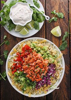 two white plates filled with different types of food on top of a wooden table next to a bowl of guacamole