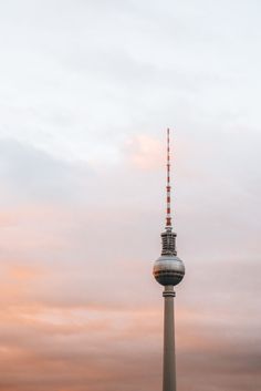 a tall tower with a sky background and clouds in the foreground, at sunset