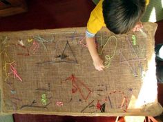 a little boy that is standing in front of a piece of cloth with letters and numbers on it