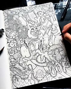 a person is holding a pen and drawing on a paper with doodles in front of them