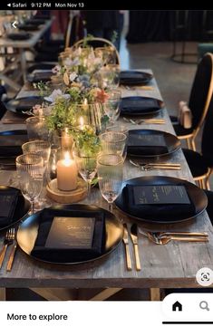 a table set with black plates and place settings, candles on each plate for dinner