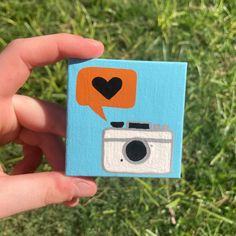 a hand holding up a small card with an image of a camera and speech bubble