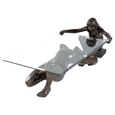 a bronze figurine sitting on top of a glass table