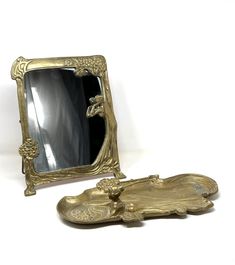 an antique mirror and tray are sitting next to each other