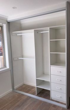 an empty closet with white shelves and drawers in the corner, next to a window