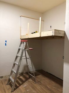 a ladder that is sitting in front of a wall with a shelf on top of it