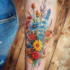 a woman's leg with flowers and watercolors on it, in front of a wooden floor