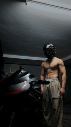 a shirtless man standing next to a motorcycle