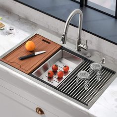 a kitchen sink with cutting board, knife and oranges