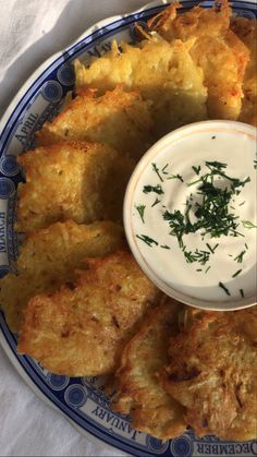 a blue and white plate topped with fried food next to a small bowl of ranch dressing