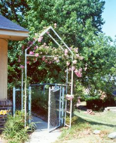 an iron gate with pink flowers on it in front of a house