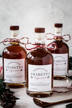 three bottles of amarreto are sitting on a table next to some pine cones