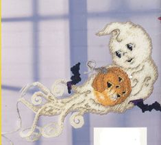 there is a cross - stitch picture of a ghost and a pumpkin hanging on the wall