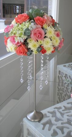 a vase filled with lots of flowers on top of a table next to a window