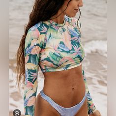 Billabong Rides And Tides Long Sleeve Cropped Rashguard For Women Green Beachy Long Sleeve Tops For Beach Party, Beachy Long Sleeve Tops For Poolside, Tropical Long Sleeve Swimwear For Beach Party, Tropical Fitted Top For Beach Party, Fitted Tropical Top For Beach Party, Multicolor Tops For Surfing, Beach Season, Multicolor Tops For Surfing Beach Season, Tropical Printed Tops For Swimming, Beachy Multicolor Tropical Print Tops