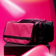 a pink and black bag sitting on top of a wooden table next to a red wall