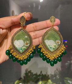 These handmade resin earrings feature a white flower encased in a green shimmering background, complemented by gold bezel and green beads. ✨You can customize it with your name(up to 5 characters) in English,Urdu, Arabic ✨Can change the background colour. 🌸option: Red, green, bright yellow, neo green, light and dark purple, black, dark grey, Light blue, orange, pink, maroon, baby pink, beige. ✨Can change beads. 🌸options: baby pink, green, aqua green, beige, blue, red, black, orange, yellow, pin Green Aqua, Name Initials, Green Beads, Fancy Jewellery, Grey Light, Green Beige, Resin Earrings, Aqua Green, Pink Beige