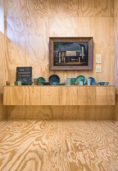 a wooden table topped with lots of blue glass bowls next to a painting on the wall