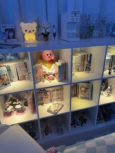 a white book shelf filled with lots of books next to a stuffed animal on top of it