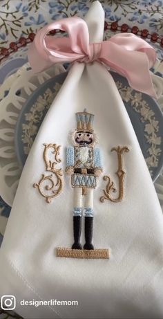 a white table cloth with a nutcracker on it and a pink bow hanging from the top