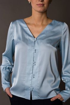 "A beautiful satin blouse featuring button front closure, long sleeves with cuffs, and a v-neckline. - v-neckline - fabric button front closure - long sleeves with cufffs - shift silhouette Color: light blue Fabric: Viscose - 30, polyester - 65%, elastane - 5%. Our model wears size US 8 and is 171cm/5'6\" tall. You may feel free choosing the size. Just send us your measurements (bust, waist, hips, height). We will define your correct size. SIZE CHART XS __ EU 34 __ US 4 bust: 31,5\" | 80 cm wais Silk V-neck Blouse With Button Closure, Elegant V-neck Top With Button Cuffs, Spring Satin Blouse With Button Closure, Spring Satin Blouse With Buttons, Satin Blouse With Buttons For Spring, Satin Top With Button Closure, Elegant Satin Tops With Button Cuffs, Solid Satin Top With Button Closure, Satin Button-up Top With Buttons