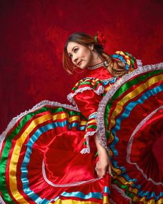 a woman in a colorful mexican dress posing for a photo with her arms spread out