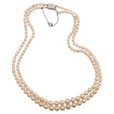 Dating to approximately 1940, this luxurious strand of luminous, gleaming nearly-antique cultured pearls is so fine in quality it rivals -and in some ways surpasses- that of natural, uncultured pearls. Composed of 155 creamy white graduated cultured Akoya pearls. measuring from 3mm to just above 8mm, this double-strand necklace features an exquisite 18K clasp set with four small, beautiful old-cut diamonds. The clasp bears marks from France. These pearls hail from the early days of the cultured pearl farming industry. As such, they were allowed to remain in the cold seawater for a longer period of time than modern Akoya pearls. The resulting pearls have thick nacre that gives them the luminous look of natural pearls, which are solid nacre. The pearls also have surface blemishes and imperfe Formal Double Strand Pearl Necklace With Pendant, Double Strand Pearl Necklace For Formal Occasions, Formal Double Strand Pearl Necklace, Vintage Akoya Pearl Drop Necklace, Vintage Akoya Pearl Necklace For Formal Occasions, Formal Vintage Akoya Pearl Necklace, Classic Double Strand Pearl Pendant Necklace, Classic Double Strand Pearl Necklace With Pendant, Classic Evening Pearl Necklace With Round Beads