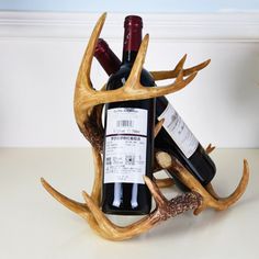 there is a wine bottle holder made out of deer antlers and some bottles in it