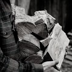 black and white photograph of someone holding a pile of logs in their hands with wood shavings on them