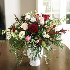 a white vase filled with lots of flowers on top of a wooden table