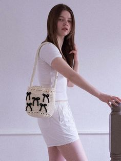 a woman in white dress carrying a crocheted purse