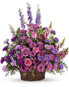 a basket filled with lots of purple and pink flowers on a white background, it's all in bloom