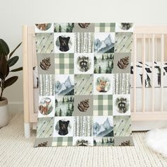 a baby crib with a blanket that has pictures of animals and pine cones on it