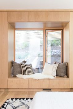 a bed sitting under a window in a bedroom next to a white rug on top of a hard wood floor