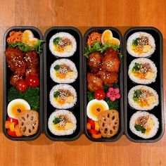 four black trays filled with different types of food on top of a wooden table