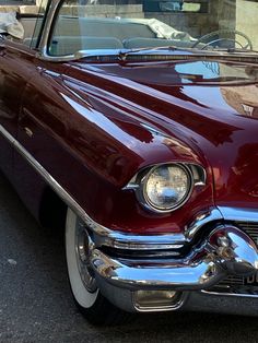 an old red car parked on the side of the road