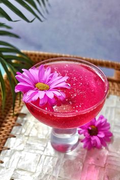 a pink drink with purple flowers in it