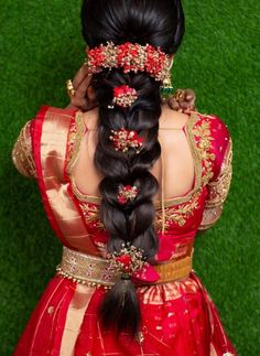 a woman with long black hair in a red and gold dress, braided into a ponytail