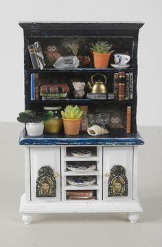 a miniature cabinet with books and plants on it