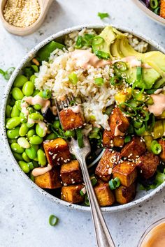 a bowl filled with rice, peas and tofu