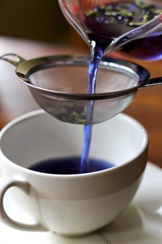 a cup filled with blue liquid being poured into the coffee filterer to make it taste like something out of a teapot