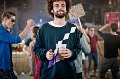 a man standing in front of a group of people holding up signs and drinking beer