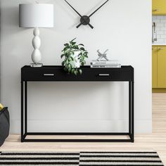 a black and white table with a plant on it in front of a wall clock