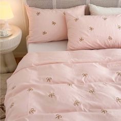 a bed with pink sheets and pillows on it