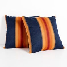 two blue and orange striped pillows against a white wall